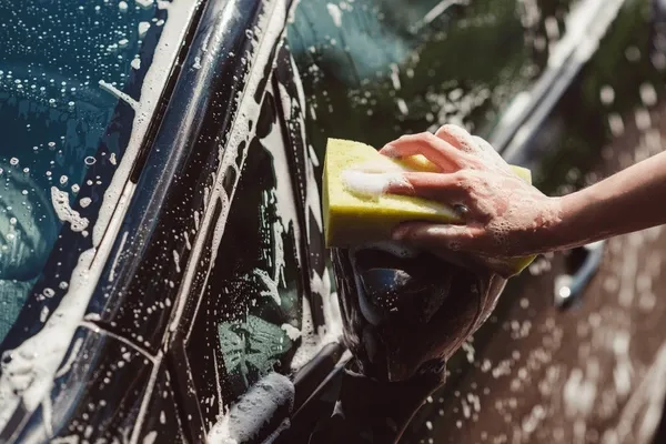 Hand washing a car with sponge and soapy water